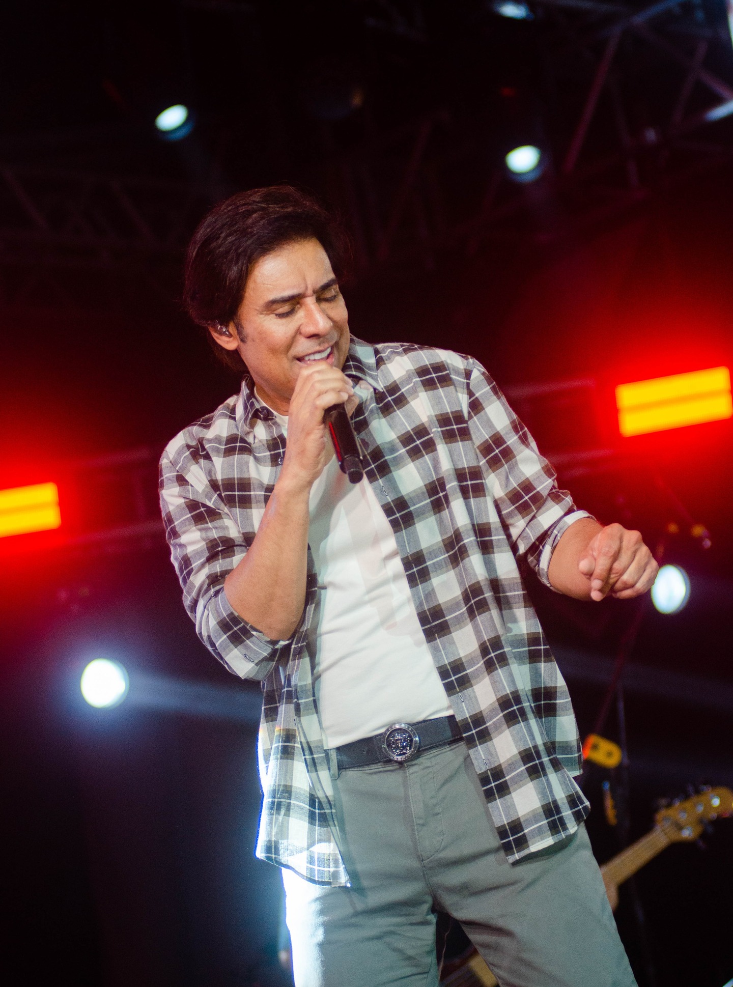 Cantor sertanejo se apresentando sob luzes vermelhas